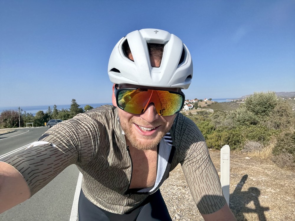 Helmet-and-sunglasses selfie of Sven riding a road bike on a sunny coastal road