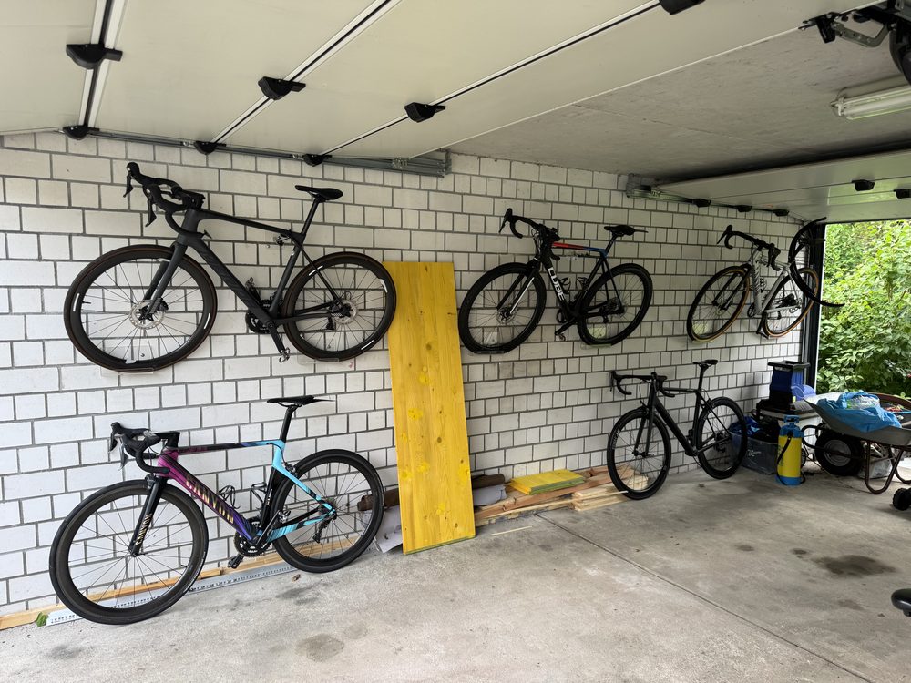 Several road and gravel bikes mounted on a white-tiled garage wall