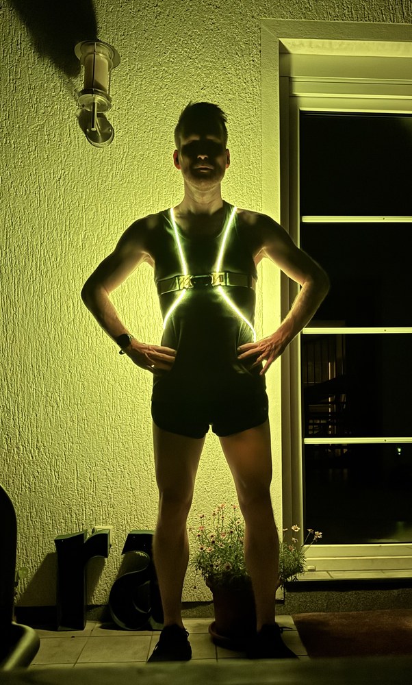 Sven standing at night wearing a glowing LED reflective running vest