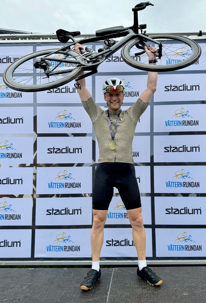 Sven holding his road bike overhead on the Vätternrundan finish podium